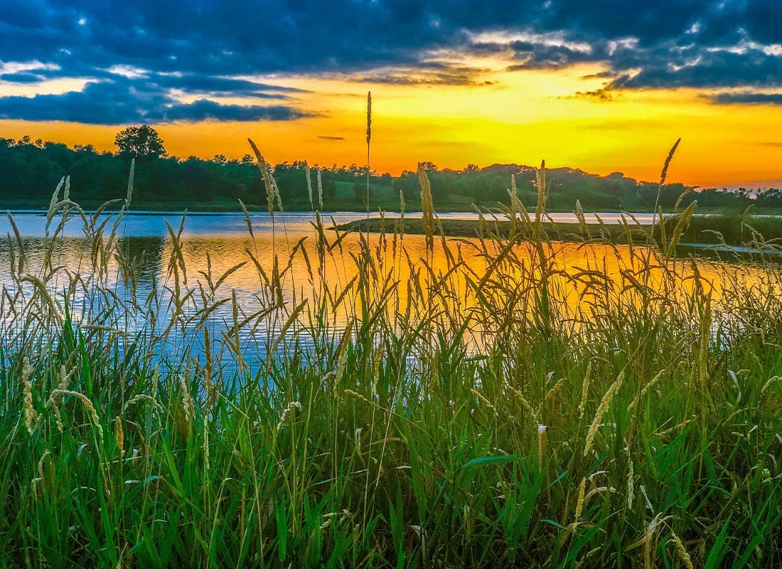 Emerson, IA - Tall Grass by a Small Lake With a Beautiful Sunset in the Background